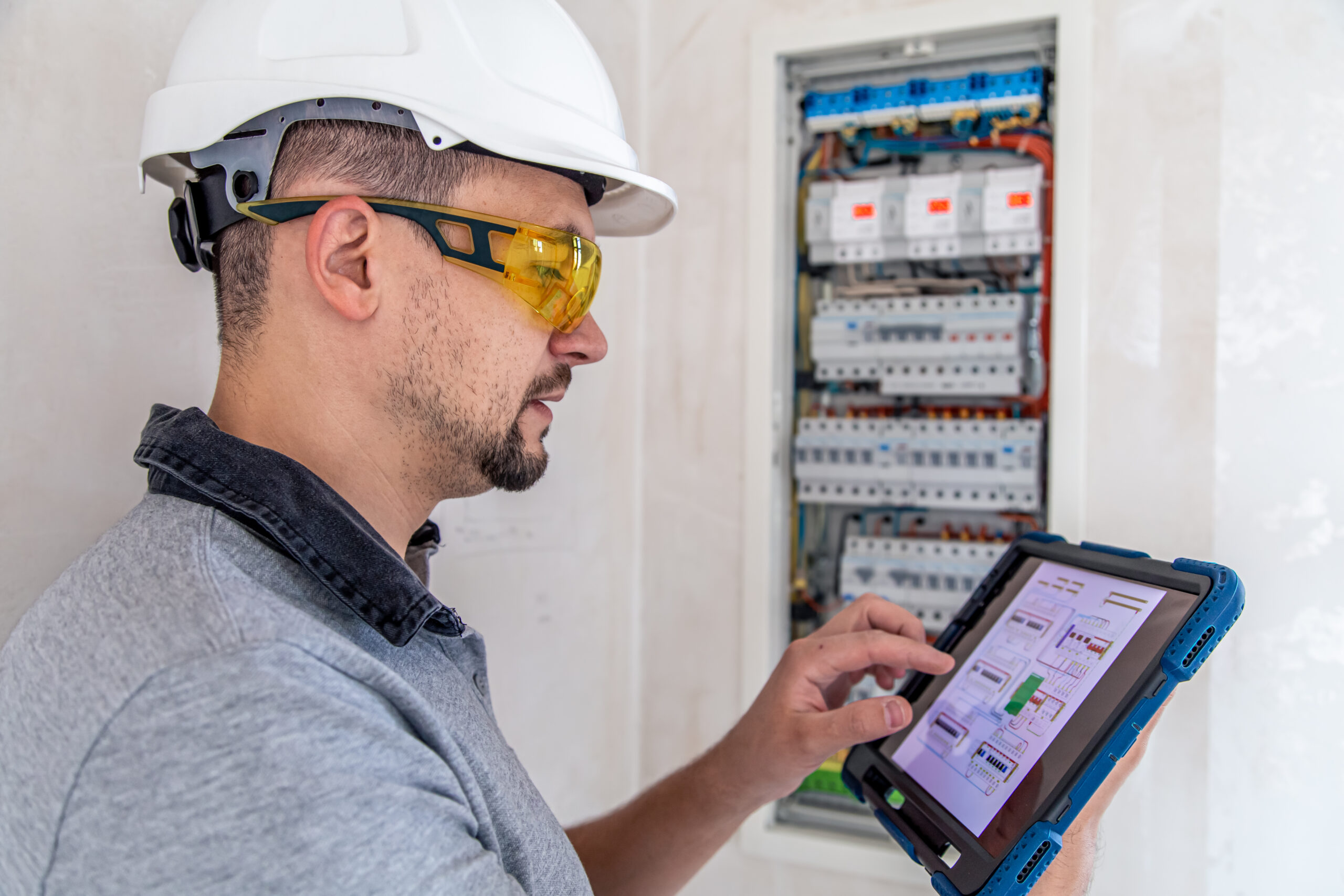 Electrical technician looking focused while working in a switchboard with fuses.
