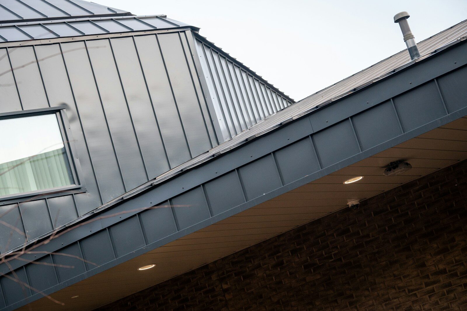 Modern building with metal roof and brick facade.